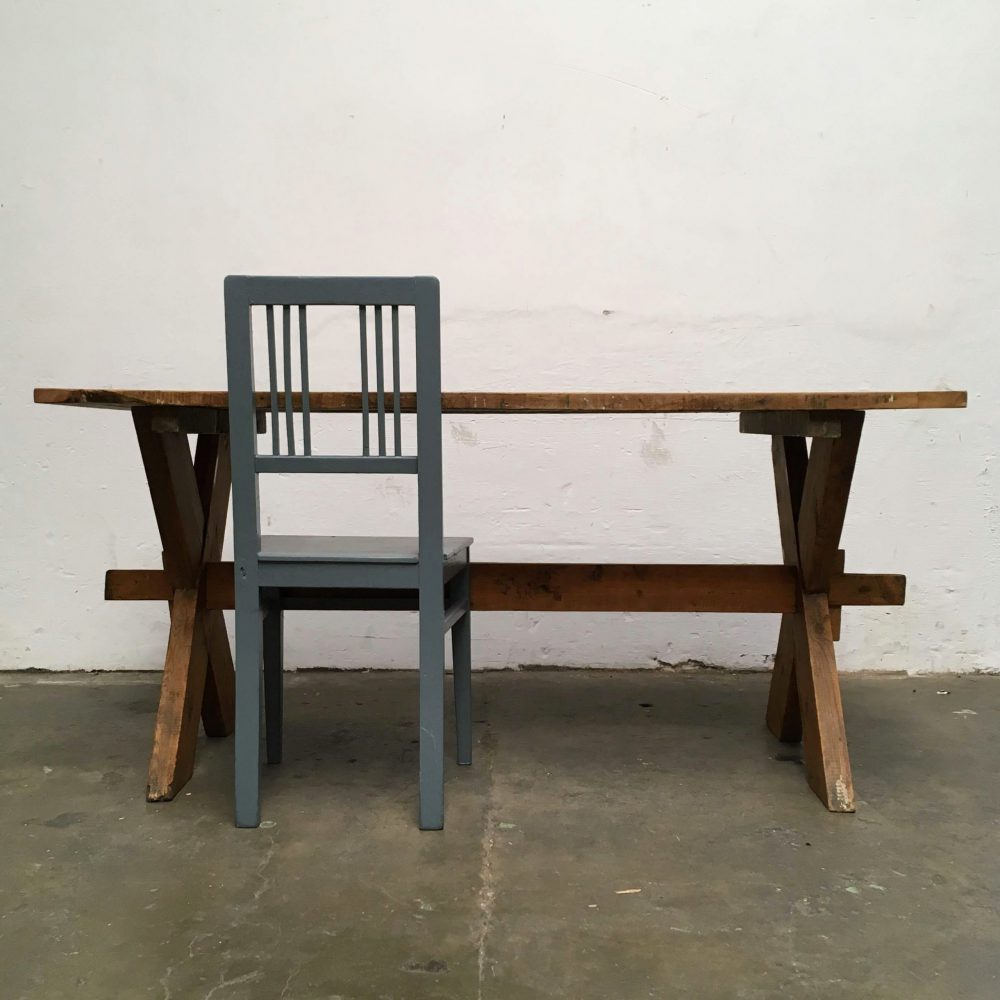 Industriële houten kruispoot tafel met grijze stoel.