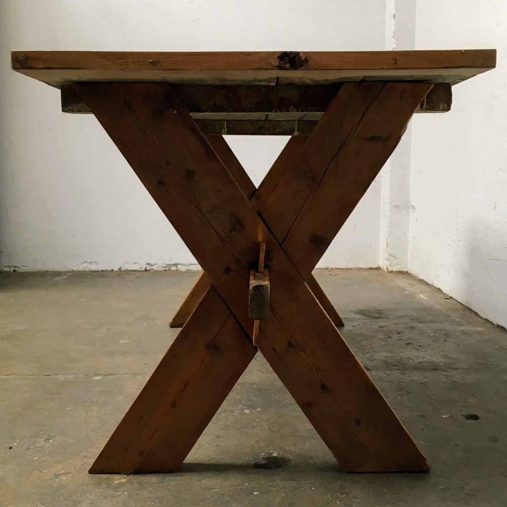 Poten van een industriële houten kruispoot tafel.
