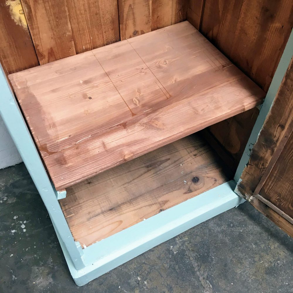 Plank binnenin blauwe houten 1-deurs kast.