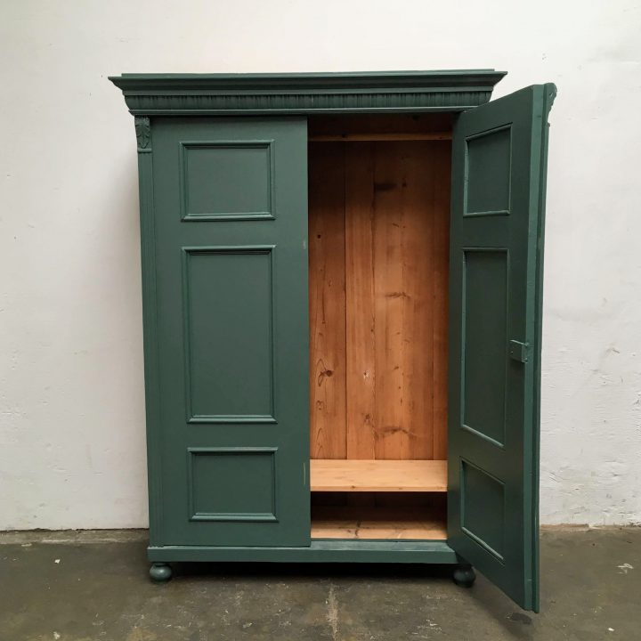 Een donkergroene houten twee deuren kast met een open deur.